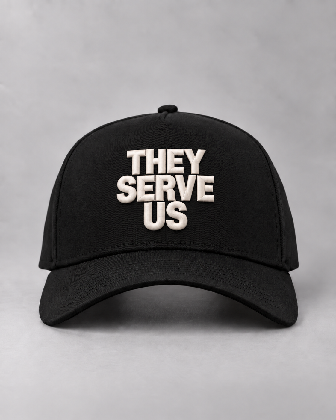 Front view of the black THEY SERVE US cap with raised ivory lettering.
